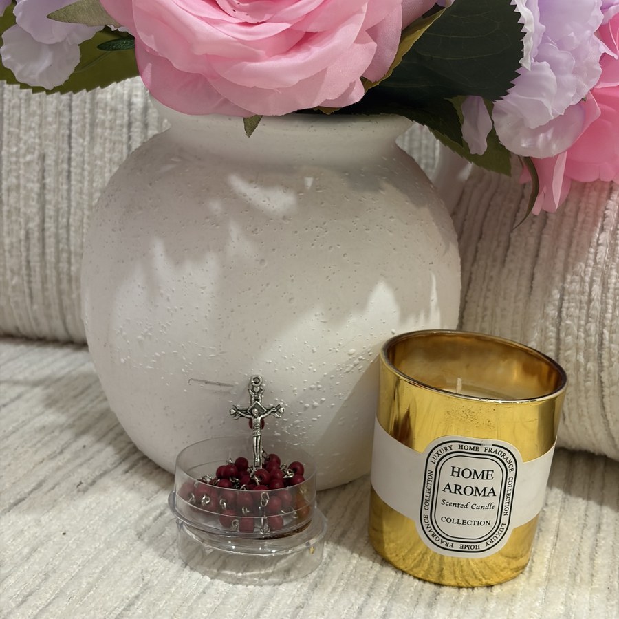 Jerusalem rosary displayed with a candle in a styled vase